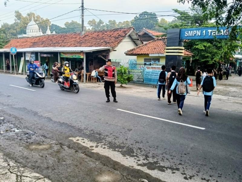 Bhabinkamtibmas Polsek Telagasari Pastikan Siswa Menyebrang dengan Aman