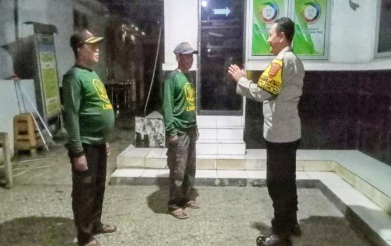 Bhabinkamtibmas Polsek Telukjambe Timur Ngobrol Santai Bareng Anggota Linmas di Halaman Kantor Desa Sirnabaya