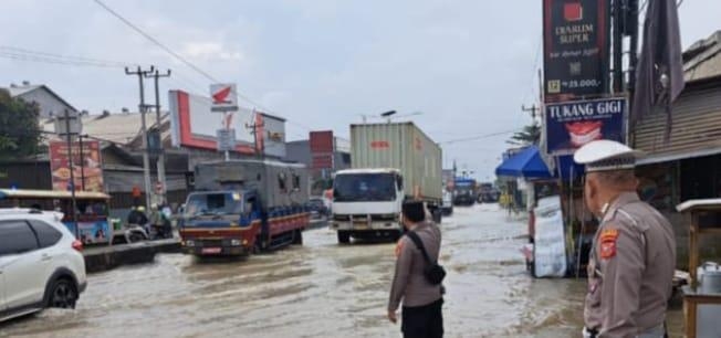 Respon Cepat Polsek Klari Lakukan Gatur dan Penguraian Kemacetan di Titik Banjir Usai Hujan Deras