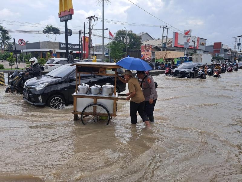 Jalan Raya Banjir, Anggota Polsek Klari Sigap Bantu Pedagang Dorong Gerobak