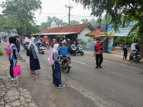 Bhabinkamtibmas Polsek Telagasari Aiptu Yosep Bantu Siswa Menyebrang Saat Gatur Pagi